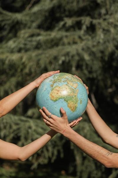 Two sets of hands holding a globe of the Earth