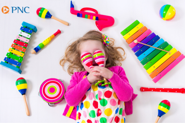 A young child poses with a variety of musical instruments
