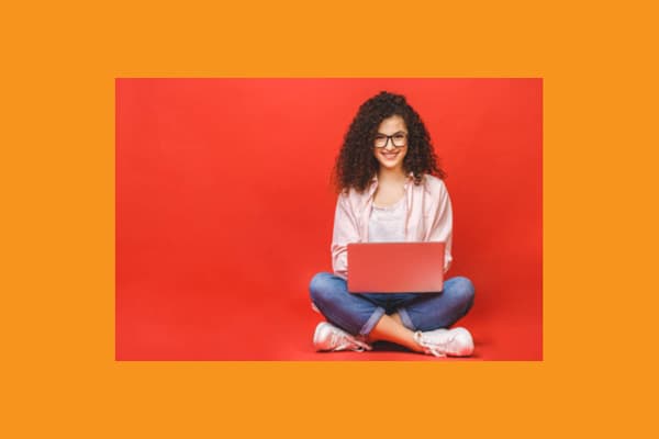 A curly haired teen girl uses a laptop computer in a red box surrounded by orange